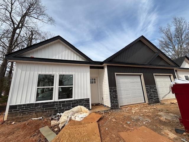 view of front facade featuring board and batten siding, an attached garage, and stone siding