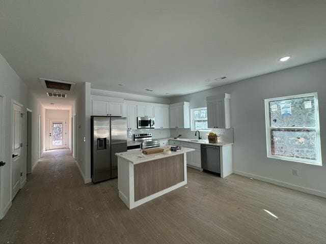 kitchen featuring stainless steel appliances, a center island, white cabinets, and light wood-style floors