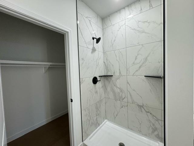 bathroom featuring a spacious closet, a shower stall, and baseboards