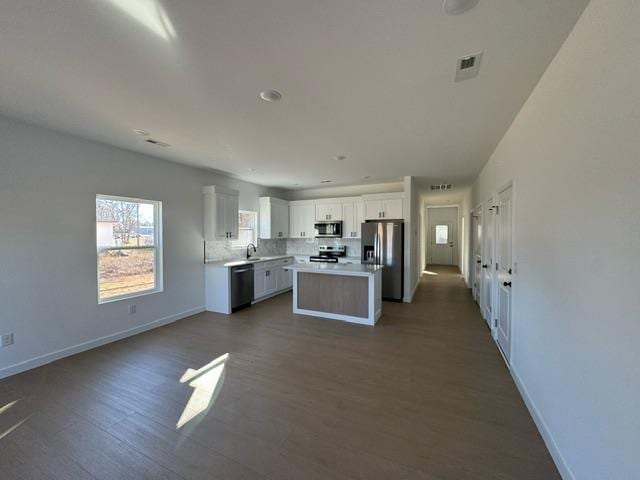 kitchen featuring dark wood-style floors, appliances with stainless steel finishes, white cabinets, light countertops, and baseboards