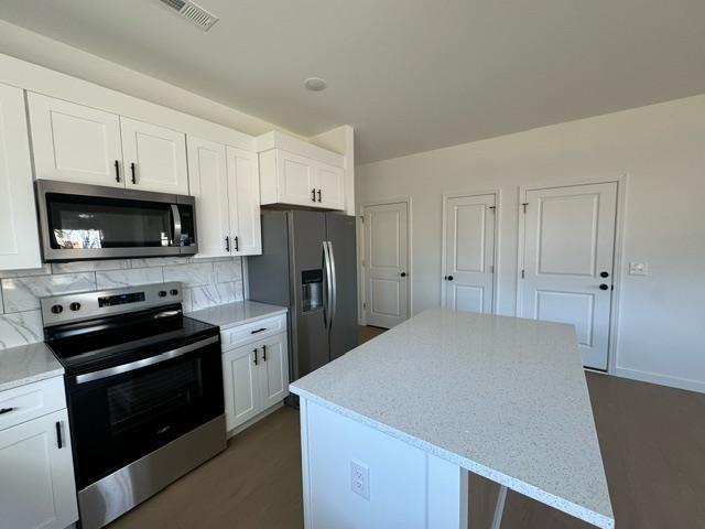 kitchen featuring tasteful backsplash, visible vents, a center island, appliances with stainless steel finishes, and white cabinets