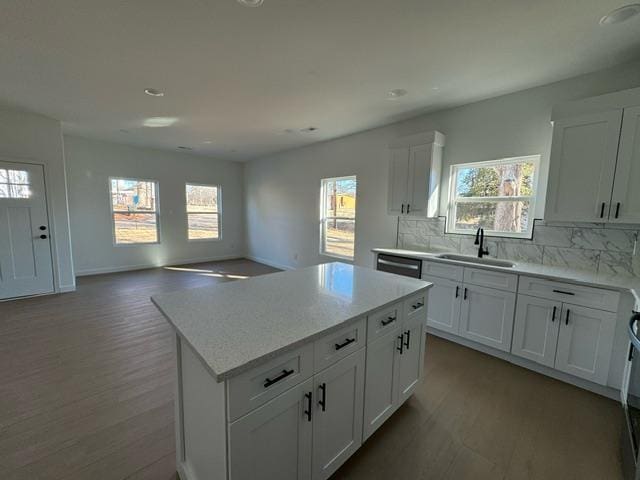 kitchen with a wealth of natural light, a sink, wood finished floors, a center island, and decorative backsplash