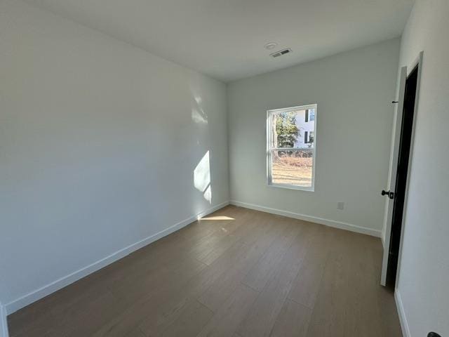 empty room featuring visible vents, baseboards, and wood finished floors