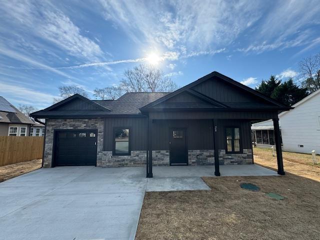 view of front of property featuring a garage, fence, board and batten siding, and concrete driveway