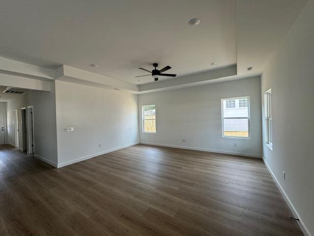 spare room featuring a raised ceiling, dark wood finished floors, and baseboards