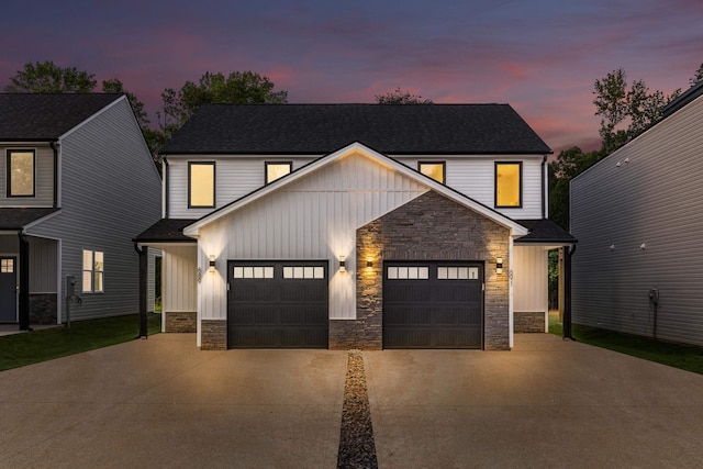 view of front facade featuring roof with shingles, an attached garage, concrete driveway, stone siding, and board and batten siding