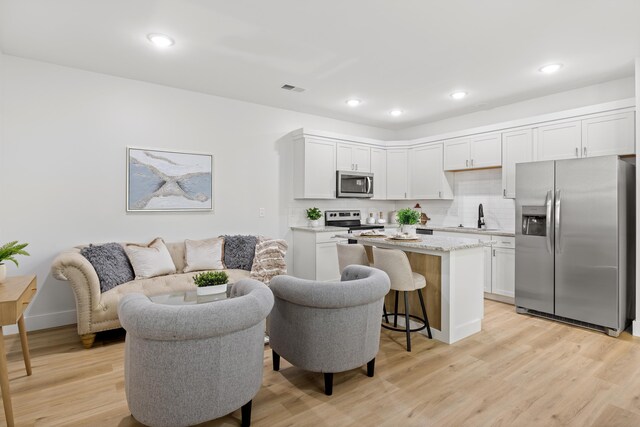 kitchen with visible vents, light wood-style flooring, a sink, a kitchen island, and appliances with stainless steel finishes