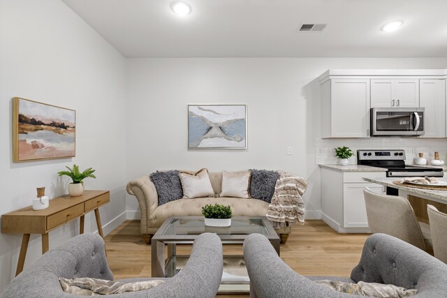 living area featuring visible vents, recessed lighting, baseboards, and light wood-style floors