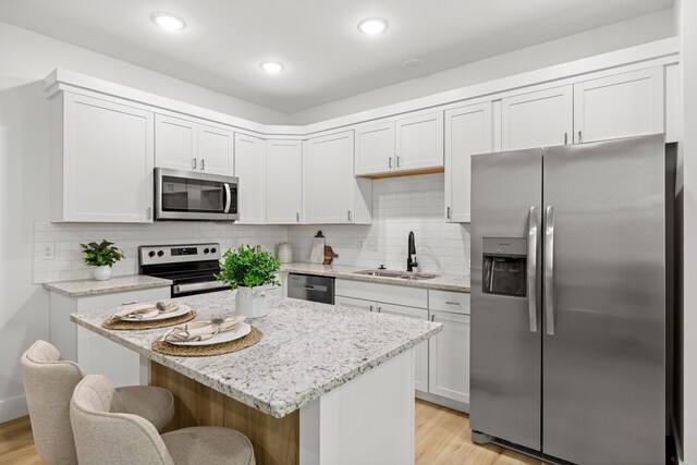 kitchen with a sink, a breakfast bar area, light wood finished floors, and stainless steel appliances