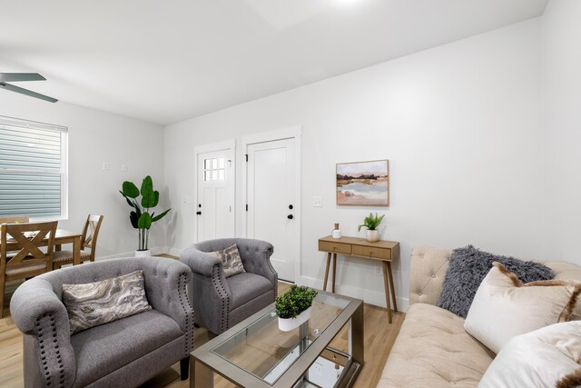 living room with baseboards, plenty of natural light, a ceiling fan, and light wood finished floors