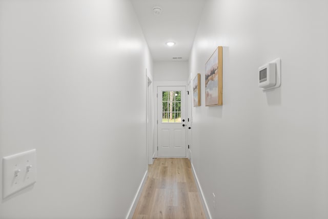 hall with baseboards and light wood-style floors