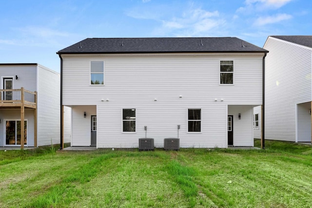 back of property with central air condition unit and a lawn