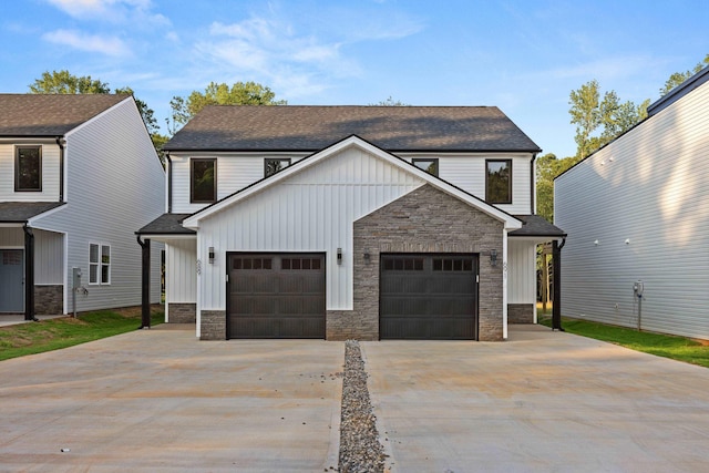 view of front of house with board and batten siding, a shingled roof, driveway, stone siding, and an attached garage