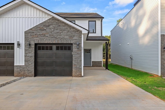 view of front facade with stone siding, board and batten siding, driveway, and a garage