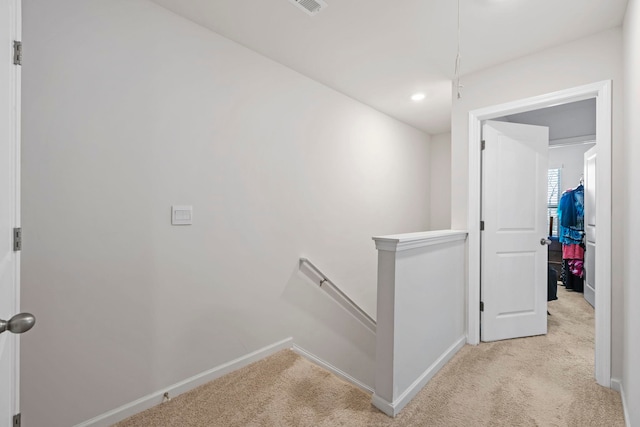 hall featuring an upstairs landing, light colored carpet, and baseboards