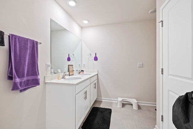 bathroom with double vanity, recessed lighting, baseboards, and a sink