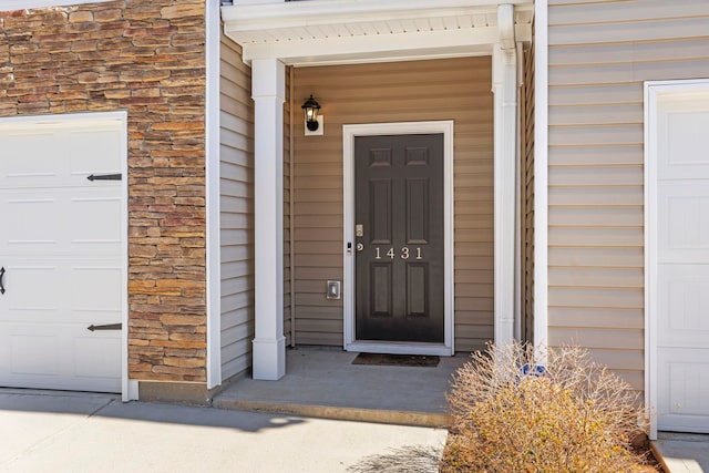 view of exterior entry with stone siding and a garage