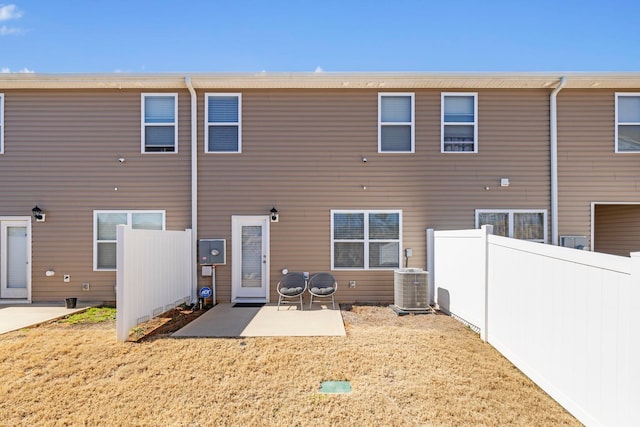 back of property with central air condition unit, fence, a yard, and a patio area