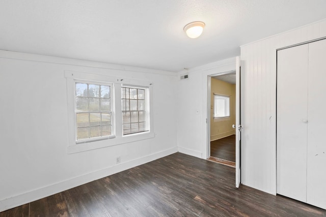 unfurnished bedroom with a closet, visible vents, baseboards, and wood finished floors