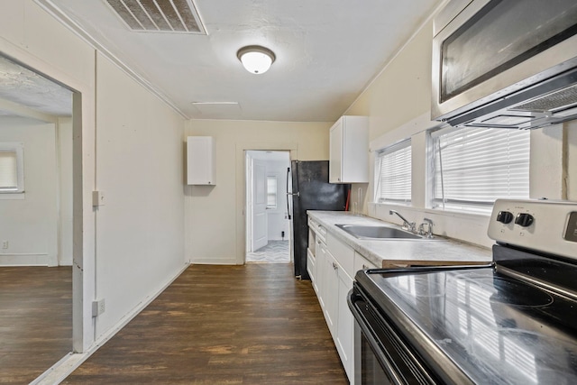 kitchen with dark wood-style floors, white cabinets, appliances with stainless steel finishes, and a sink