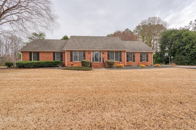 ranch-style house featuring brick siding, a front lawn, and a shingled roof