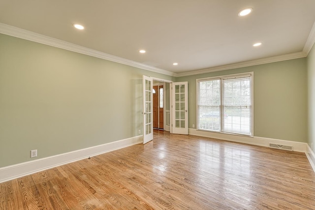 empty room with visible vents, baseboards, light wood-style floors, and crown molding