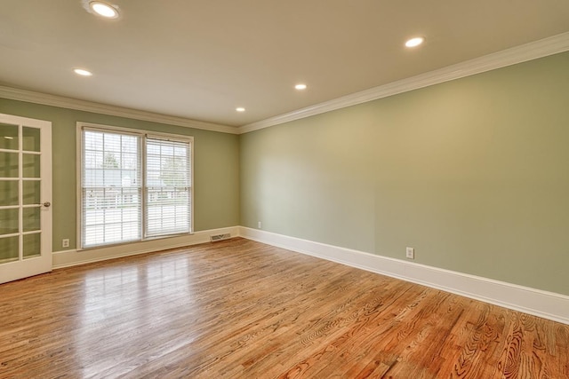 empty room featuring light wood finished floors, visible vents, baseboards, ornamental molding, and recessed lighting