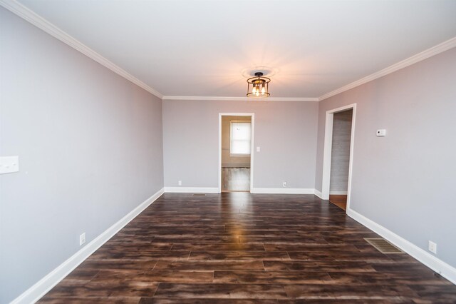 spare room featuring crown molding, dark wood-type flooring, and baseboards