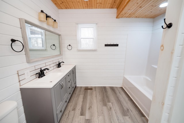 bathroom featuring toilet, wood ceiling, wood finished floors, plenty of natural light, and a sink