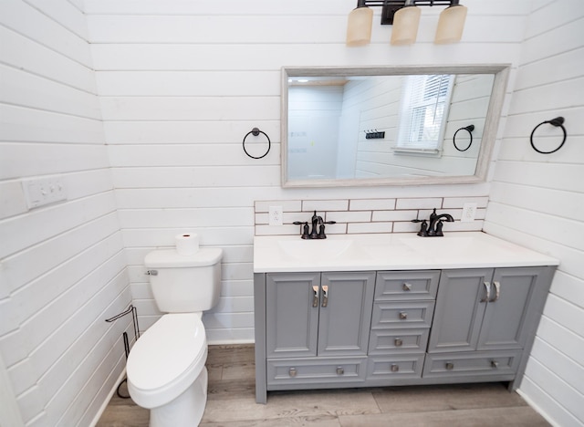 bathroom featuring a sink, toilet, wood finished floors, and double vanity