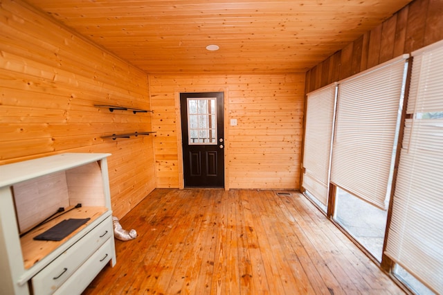 interior space with wooden ceiling, light wood-style flooring, and wooden walls