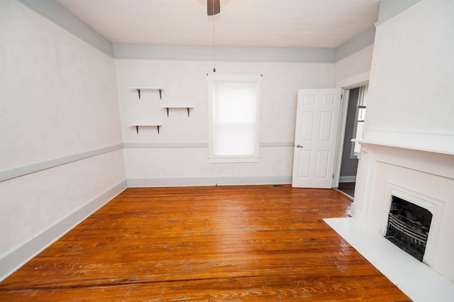 unfurnished living room featuring ceiling fan, baseboards, wood finished floors, and a fireplace
