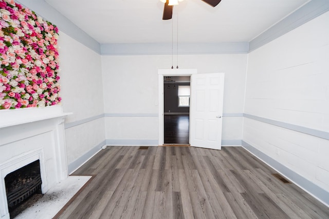 unfurnished dining area with a high end fireplace, visible vents, ceiling fan, baseboards, and wood finished floors