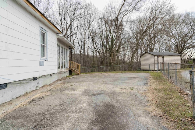 view of yard with aphalt driveway, an outdoor structure, and fence