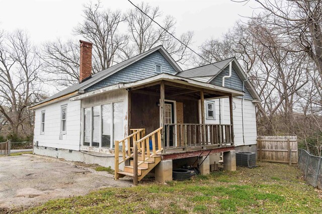 view of front of property featuring crawl space, central AC unit, a chimney, and fence