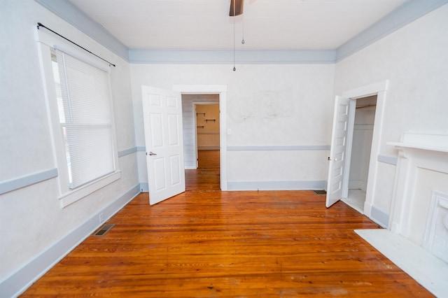 unfurnished room with visible vents, baseboards, wood finished floors, and a ceiling fan