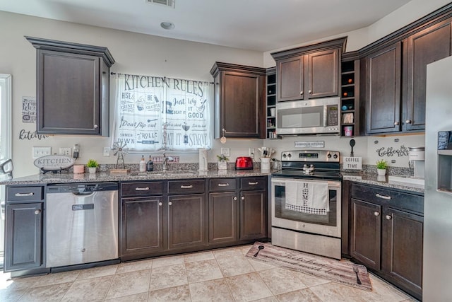 kitchen with a sink, dark brown cabinets, stone countertops, and stainless steel appliances