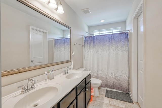 bathroom featuring a sink, visible vents, toilet, and double vanity