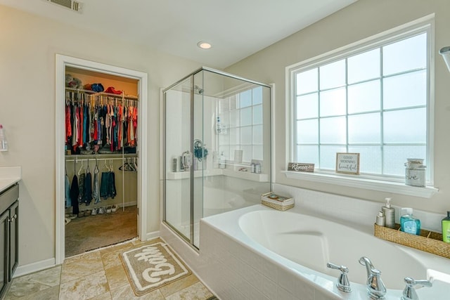 full bathroom with a spacious closet, a shower stall, and a garden tub