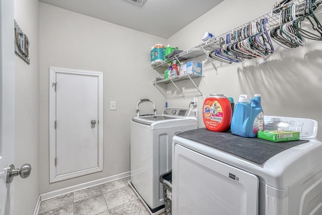 clothes washing area featuring light tile patterned floors, baseboards, independent washer and dryer, and laundry area