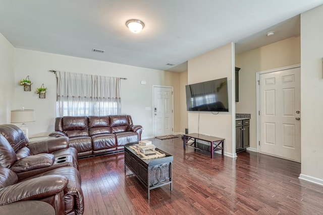 living room with visible vents, baseboards, and dark wood finished floors