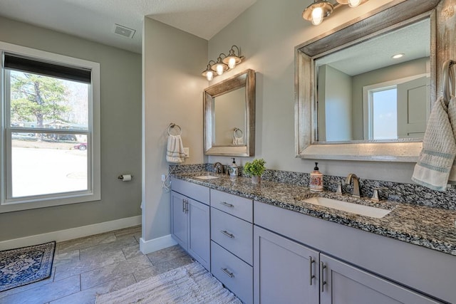 full bathroom featuring double vanity, visible vents, baseboards, and a sink