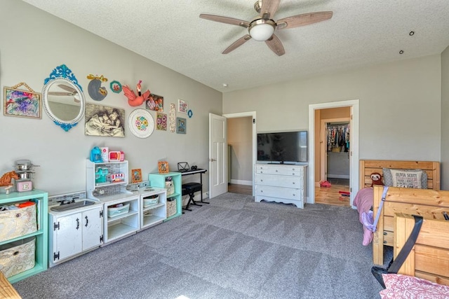 playroom featuring carpet, ceiling fan, and a textured ceiling