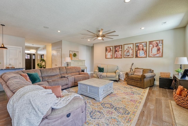 living area with ceiling fan, light wood-style flooring, recessed lighting, and a textured ceiling