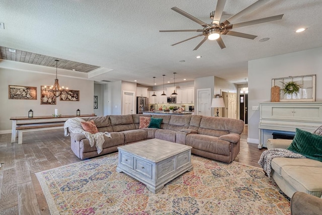 living room featuring recessed lighting, baseboards, a textured ceiling, and light wood finished floors