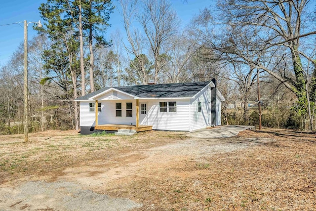 exterior space featuring driveway, covered porch, and a chimney