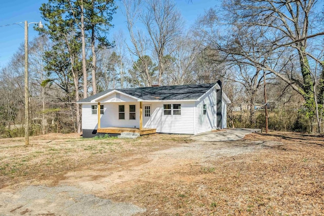 view of front of house featuring a porch, dirt driveway, and a chimney