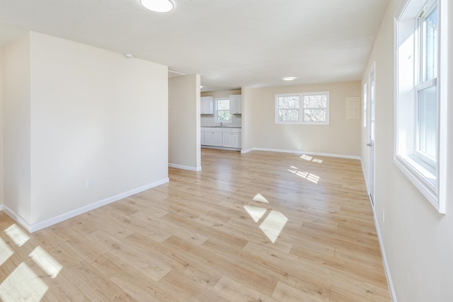 empty room with baseboards, light wood-style floors, and a sink