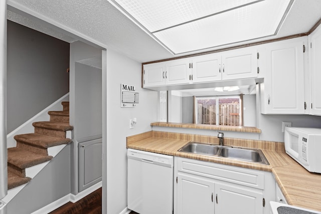 kitchen featuring white appliances, white cabinetry, light countertops, and a sink