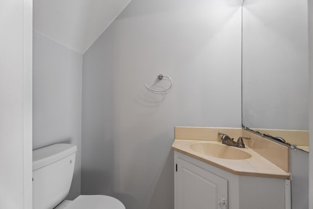 bathroom featuring lofted ceiling, toilet, and vanity